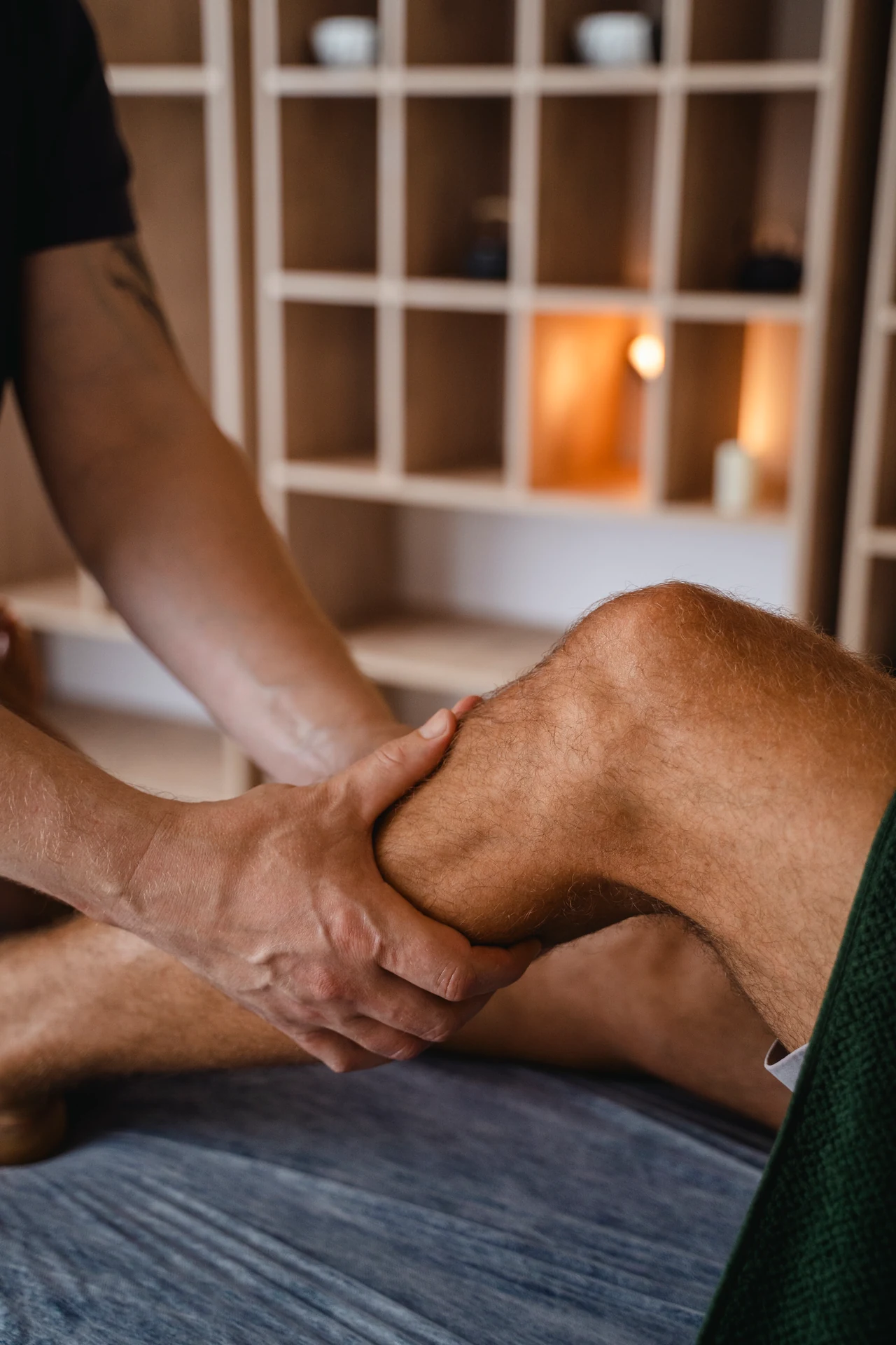 Hands supporting a patient's knee during manual therapy.